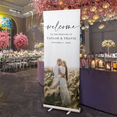 a wedding sign is displayed in front of tables with flowers and chandeliers hanging from the ceiling