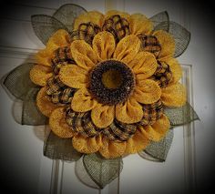 a sunflower is hanging on the front door with burlocks and plaid ribbon