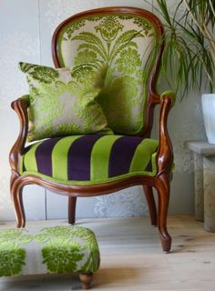 a green and purple striped chair sitting next to a potted plant on top of a hard wood floor