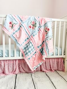 a baby crib with a pink and blue quilt on it's coverlet