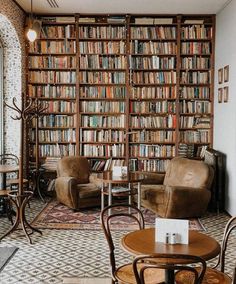 a living room filled with lots of furniture and bookshelves covered in shelves full of books