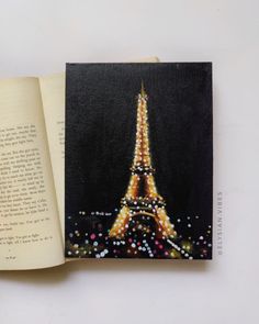 an open book with a painting of the eiffel tower on it's cover