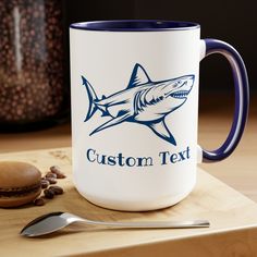 a blue and white coffee mug sitting on top of a wooden cutting board next to a spoon