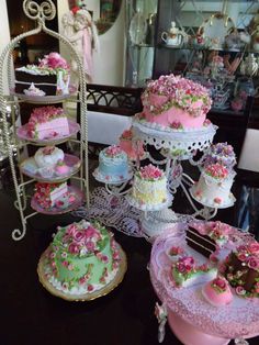 a table topped with lots of cakes covered in pink and green frosting on top of plates