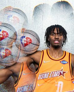 a man with dreadlocks standing in front of some basketballs