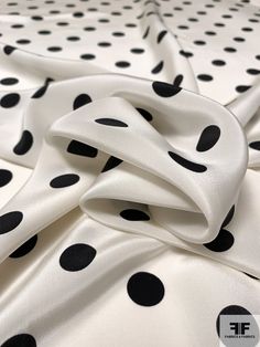 white and black polka dot fabric with large black dots on the top, as well as small black dots on the bottom