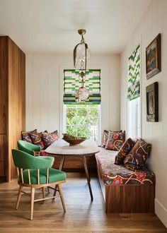 a table and chairs in a room with white walls, wood flooring and windows