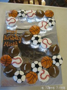 a birthday cake decorated with cupcakes and sports balls