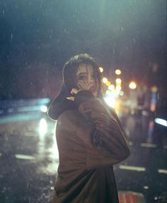 a person standing in the rain talking on a cell phone