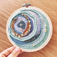 someone is stitching an embroidery project on a wooden surface