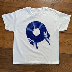 "The Record" Baby Tee Baby tee featuring iconic record graphic.  - 100% cotton - Classic fit - Runs true to size (refer to size chart) - Tear-away label - Y2K Vintage Streetwear Trending Fashion - Environmentally sustainable made-to-order system Baby tee's were popularised in the '90s, characterised by it's very short sleeves and slightly cropped body, creating a very flattering feminine shape. It originated from the skater/raver scene and was linked to the era's popular child-like fashion.  Ple Cool Graphic Tees Vintage, Unisex Blue T-shirt For Streetwear, White Unisex Pop Culture T-shirt, Unisex White T-shirt With Pop Culture Style, White Pop Culture Unisex T-shirt, Unisex 90s Style T-shirt For Fan Merchandise, 90s Style Unisex T-shirt For Fan Merchandise, Retro Screen Print T-shirt, Unisex Retro T-shirt With Screen Print