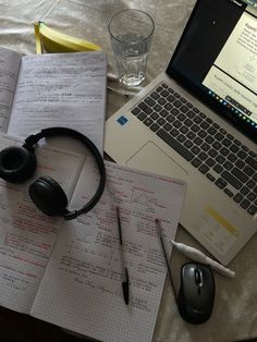 an open notebook with headphones on it next to a laptop