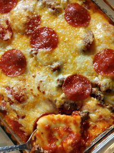 a pepperoni and cheese casserole in a glass dish with a serving spoon