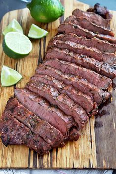 sliced flank steak with limes on cutting board