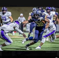 a football player running with the ball in his hand while being chased by another player