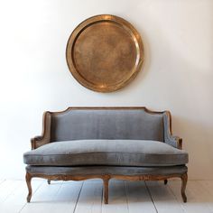 a couch sitting in front of a gold plate on the wall