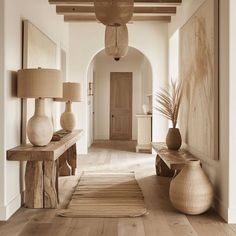 a hallway with two large vases on either side of the wall and a wooden bench