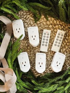 five remote controls are laying on top of some christmas wreaths and twine ribbons