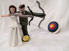 a wedding cake topper with a bow and arrow in the shape of a bride and groom