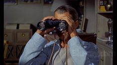 a man looking through binoculars in his kitchen