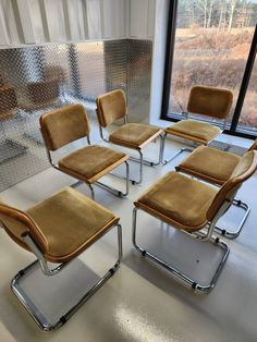 a group of six chairs sitting next to each other in front of a large window