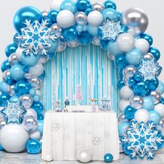 a blue and white balloon arch decorated with snowflakes