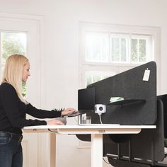 a woman standing at a desk using a laptop computer