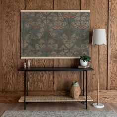 a room with wood paneled walls and a painting on the wall above a console table