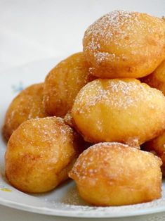 a pile of doughnuts sitting on top of a white plate covered in powdered sugar