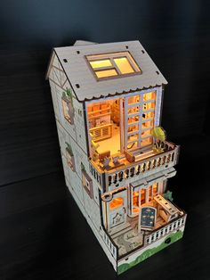 a paper model of a house that is lit up with the windows open and lights on