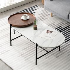 a coffee table with a magazine on it in front of a gray couch and white rug