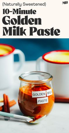 a jar of golden milk paste next to two mugs with cinnamon sticks on the side