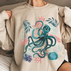 Cute octopus crewneck sweatshirt. Makes a lovely gift for nature, beach & ocean lovers as well as a cute Birthday or Christmas gift for her, mom, sister, daughter & friends! Free shipping on orders over $35 USD! Sizing: These are soft and comfy Gildan unisex sweatshirts. They are loose fitting and a bit longer than a lady's sweatshirt. Think boyfriend fit. Would advise choosing a size down for a more fitted look. For a very oversized look (thinking dress length here) size up a couple of sizes. We want you to have the perfect fit for you so please consult the size chart in the images section for full sizing information. Care Instructions: Our sweatshirts are happy to be machine washed at max 40C or 105F. Bleaching, ironing and dry cleaning makes them unhappy. They are happy to be tumble dri Selfsona Ideas, Jellyfish Sweater, Octopus Aesthetic, Ocean Sweater, Ocean Sweatshirt, Octopus Hoodie, Fish Hoodie, Ocean Outfits, Cute Wildlife