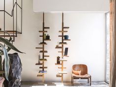 a room with a chair, bookshelf and plant on the wall next to it