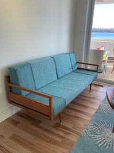 a blue couch sitting on top of a hard wood floor next to a glass door