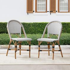 two chairs sitting next to each other in front of a building with shuttered windows