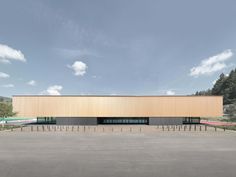 an empty parking lot in front of a large building with wooden panels on the side