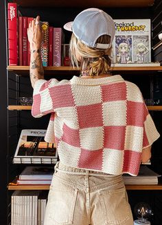 a woman standing in front of a bookshelf with her arms up to the ceiling