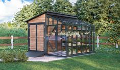 a small wooden shed with glass doors in the grass