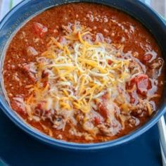 a blue bowl filled with chili and cheese