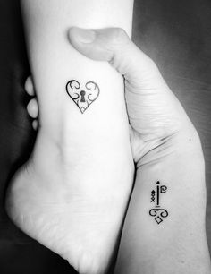 two people holding hands with tattoos on their arms and one has a key in the shape of a heart