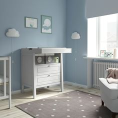 a baby's room with blue walls and white furniture