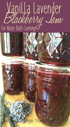 three jars filled with blueberry jam sitting on top of a wooden table next to dried lavenders