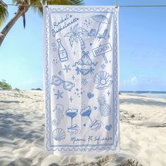 a towel hanging from a clothes line on the beach next to palm trees and water