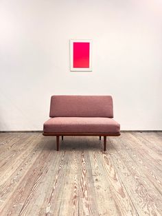 a couch sitting on top of a hard wood floor next to a red square painting