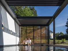 two people sitting on the edge of a swimming pool