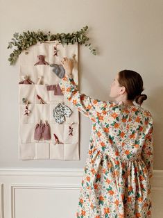 a woman standing in front of a wall hanging on the side of a white wall