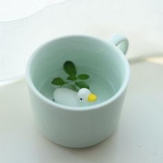 a white cup filled with water and a rubber duck floating in it's body