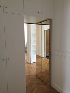 an empty room with white walls and wooden floors is seen through the door to another room