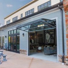 an outdoor patio with tables and benches in front of a large white building that has glass doors